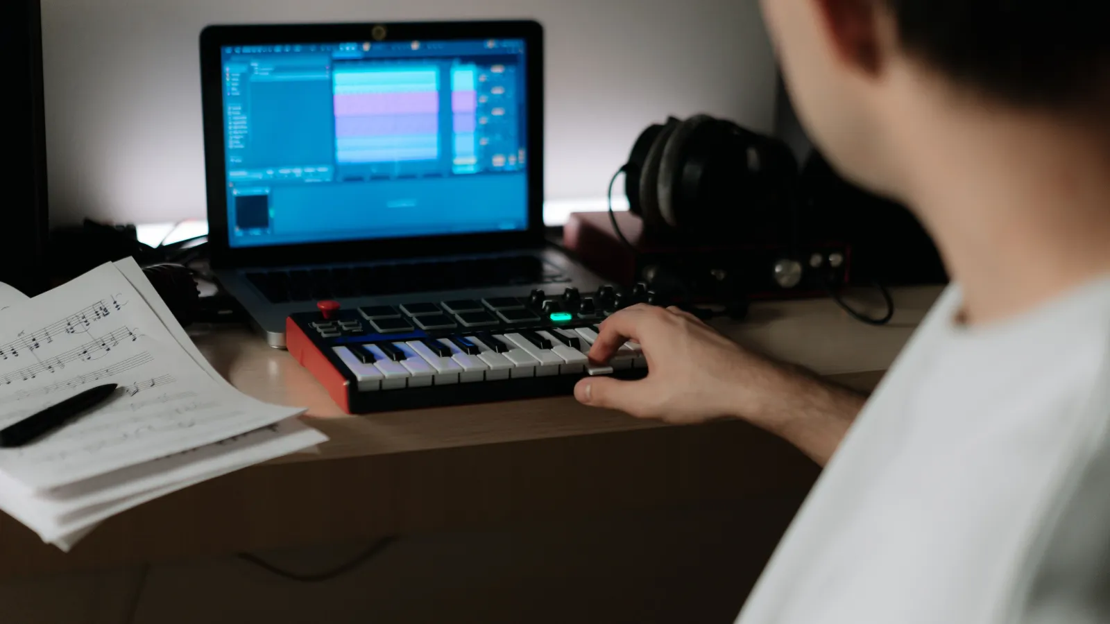 Bedroom producer making beats on a laptop DAW with a compact MIDI controller