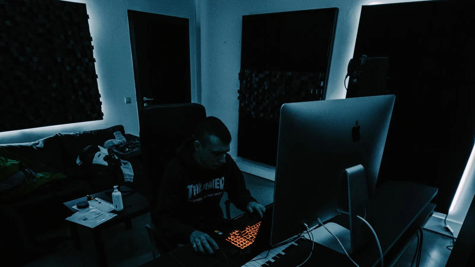 Producer working on a laptop and MIDI controller in a home studio