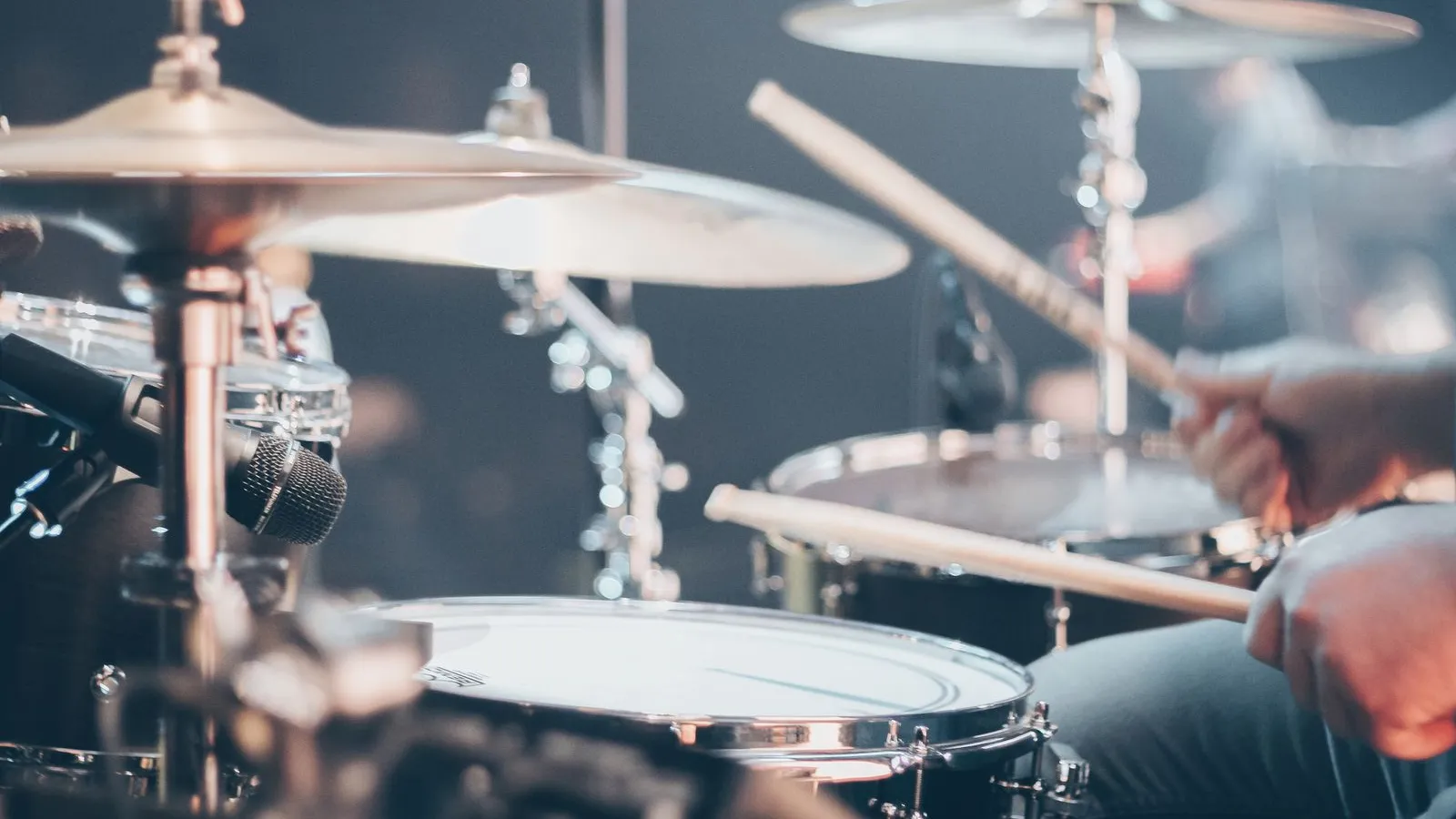 Snare drum being played with drumsticks and a microphone in a studio